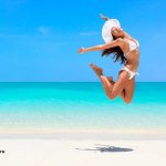 девушка прыгает от радости на берегу океана